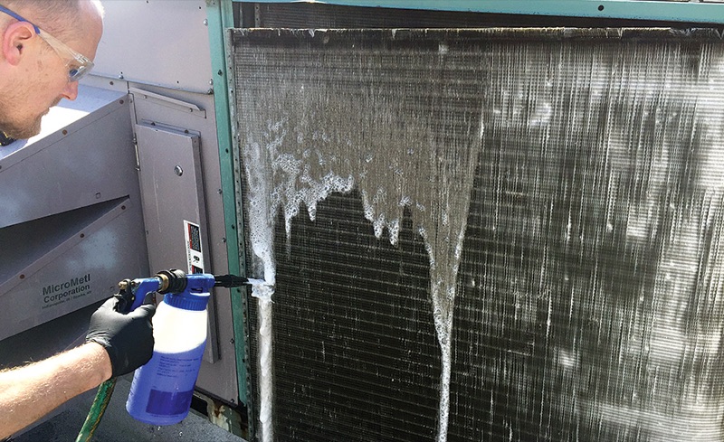 Cold Pros technician cleaning commercial condenser coils during preventive maintenance